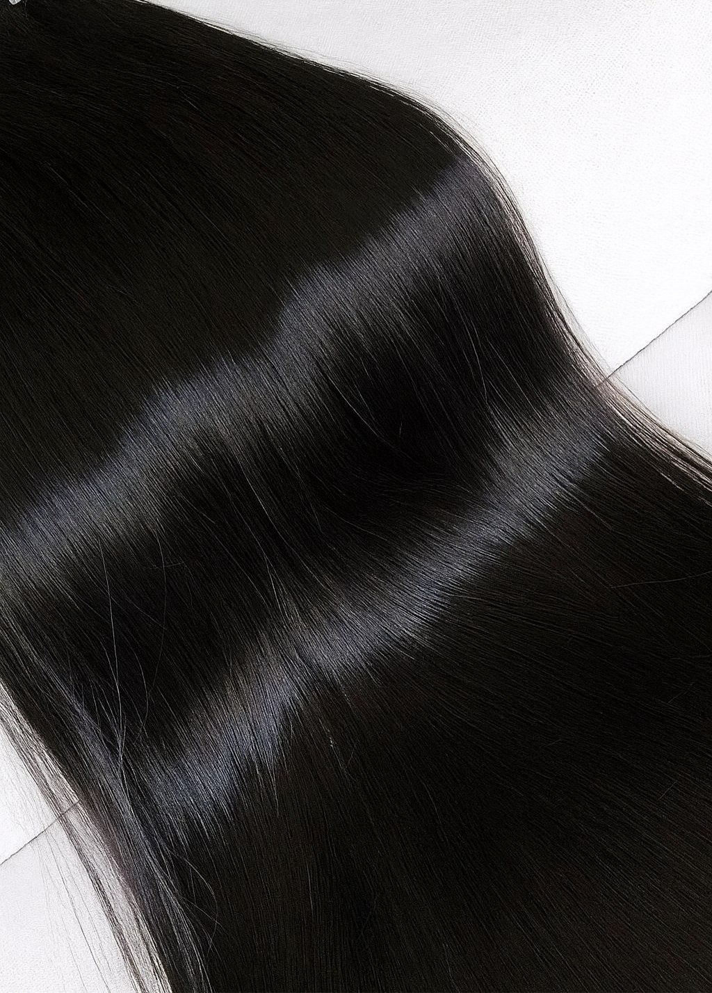 Black hair extensions on a white surface